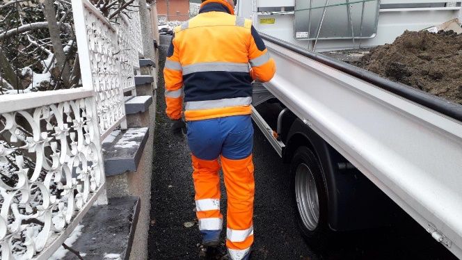 Compagnon STPS en tenue haute visibilité le long d'un camion benne